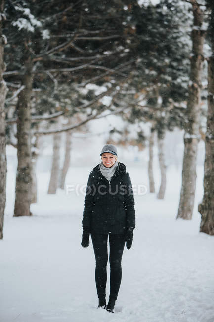 Mujer de pie en el sendero entre pinos - foto de stock