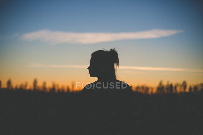 Женщина, стоящая в лесу с голубым небом — стоковое фото