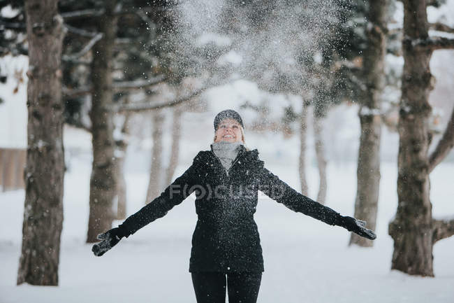 Woman standing on trail between pine trees — Stock Photo