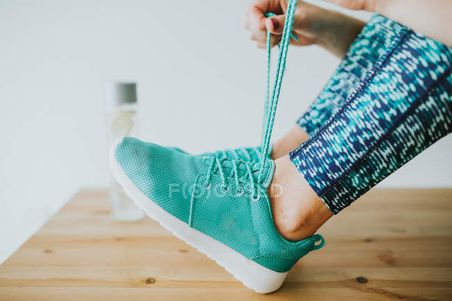 Жінка зав'язує шнурки на спортивному взутті — стокове фото