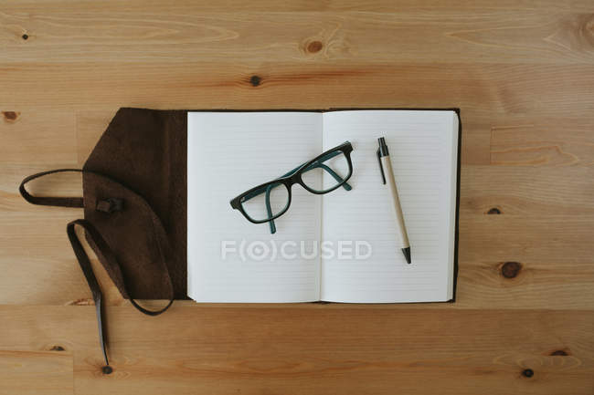 Cuaderno abierto con anteojos y bolígrafo - foto de stock
