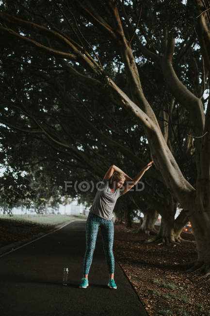 Спортивная женщина растягивается в городском парке — стоковое фото