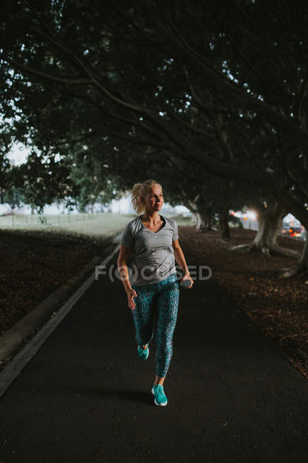 Mujer deportiva corriendo en el parque de la ciudad - foto de stock