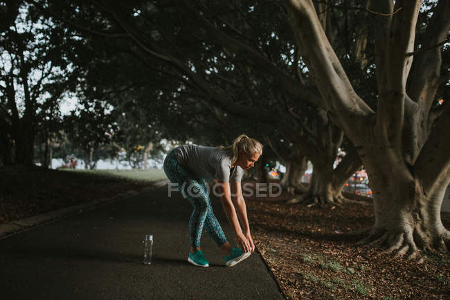 Mujer deportiva que se extiende en el parque de la ciudad - foto de stock