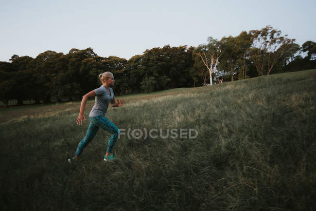 Sporty woman running on hill in park — Stock Photo
