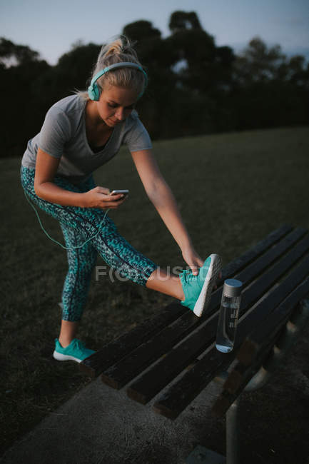 Sportliche Frau streckt sich auf Bank am Hang — Stockfoto