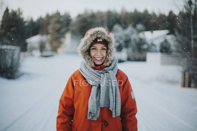 Donna in piedi in cappuccio e sorridente alla macchina fotografica — Foto stock