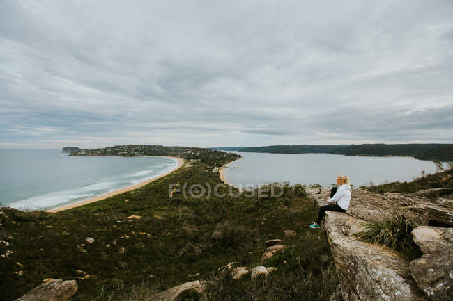 Woman sitting on rock and looking at beautiful landscape — Stock Photo