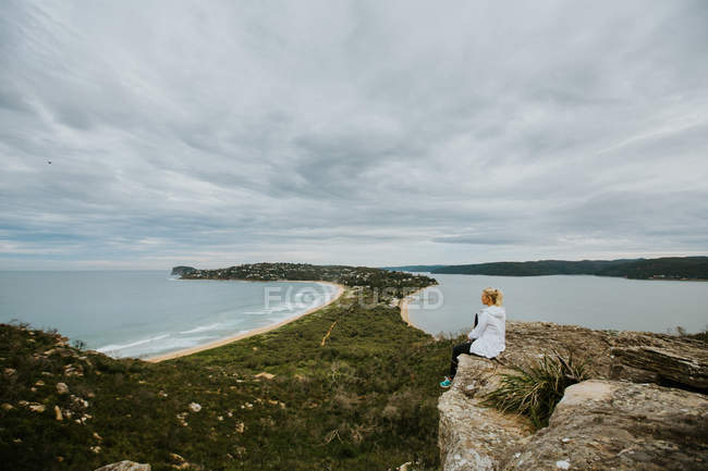 Femme assise sur le rocher et regardant un beau paysage — Photo de stock