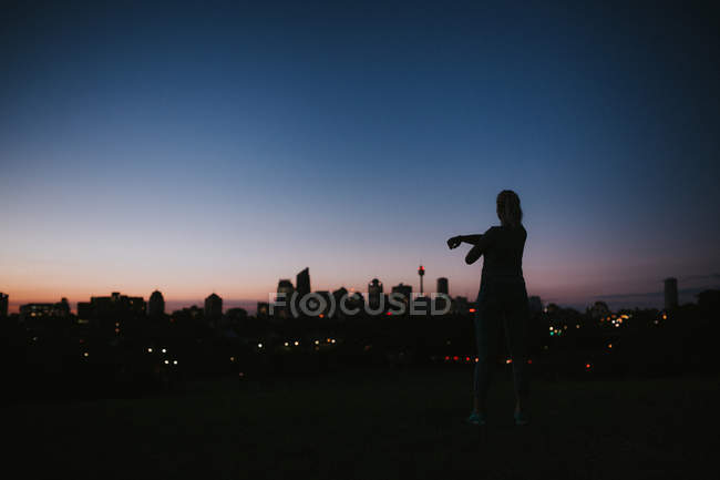 Woman stretching against city on horizon — Stock Photo