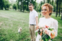 Mariée et marié en promenade avec chien — Photo de stock