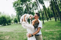 Жених и невеста веселятся с собакой — стоковое фото