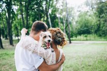 Novia y novio con perro en las manos - foto de stock