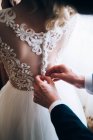 Mains de marié attacher robe — Photo de stock