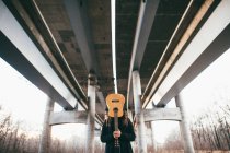 Man with guitar under bridge — Stock Photo