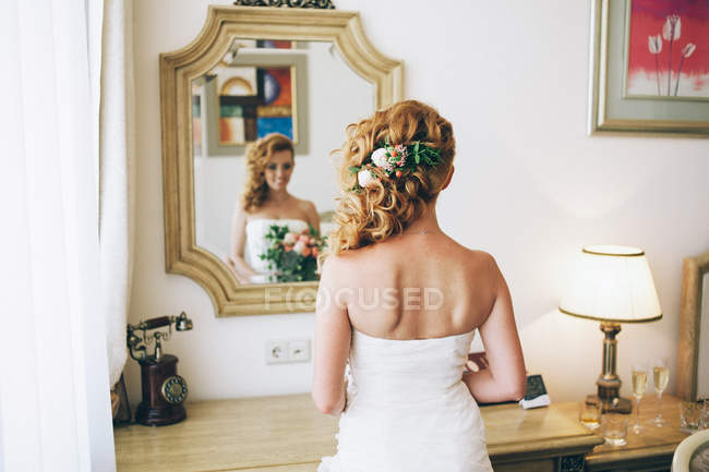 Mariée posant avec bouquet de fleurs dans le miroir — Photo de stock