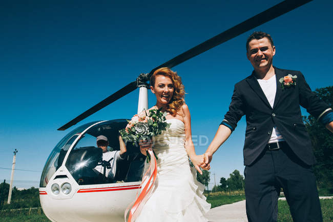 Bride and groom standing near helicopter — Stock Photo