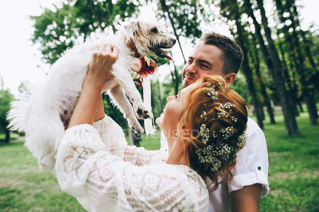 Noiva e noivo se divertindo com o cão — Fotografia de Stock
