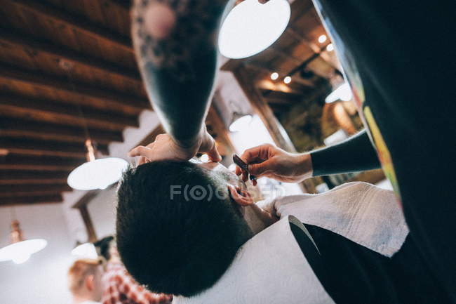 Barber making haircut to male client — Stock Photo