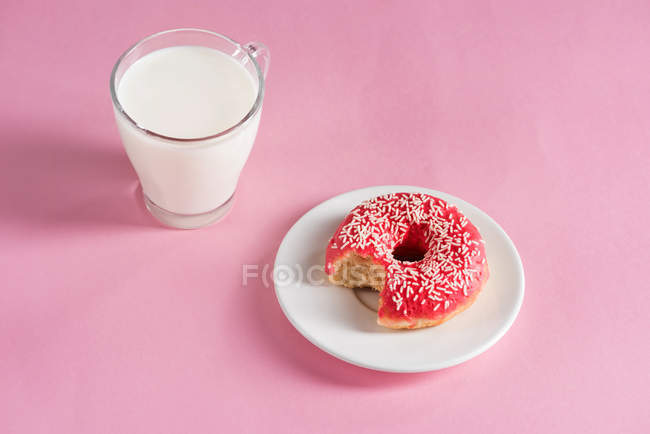 Copo de vidro de leite com donut na placa — Fotografia de Stock