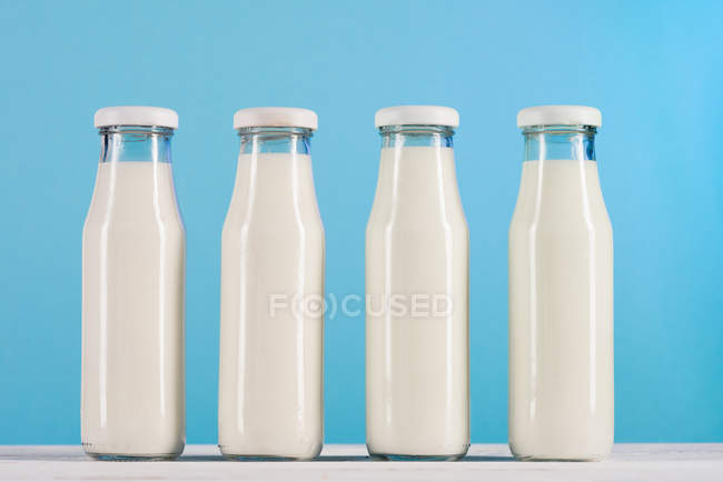 Reihe von Glasflaschen mit Milch auf der Tischplatte — Stockfoto