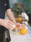 Hands cooking orange juice — Stock Photo