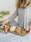 Frau hält Tafel mit Käse und Früchten — Stockfoto