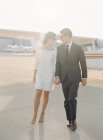 Couple walking holding hands at airfield — Stock Photo