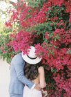 Jovem casal abraçando e cheirando flores — Fotografia de Stock
