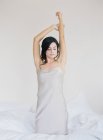 Bella donna che estende le braccia a letto — Foto stock