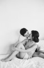 Casal sentado e beijando na cama — Fotografia de Stock