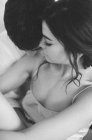 Jeune couple embrassant au lit — Photo de stock
