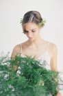 Donna che tiene foglie di felce decorativi — Foto stock