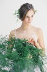 Donna che tiene foglie di felce decorativi — Foto stock
