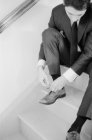 Мужчина сидит на лестнице и завязывает шнурки — стоковое фото