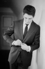 Young man doing up suit and looking away — Stock Photo