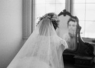 Donna in abito da sposa guardando specchio — Foto stock