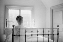 Женщина в свадебном платье сидит на кровати — стоковое фото
