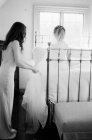 Женщина помогает невесте с свадебным платьем — стоковое фото