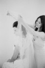 Женщина помогает невесте с покрывалом — стоковое фото