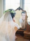 Frau im Hochzeitskleid blickt in Spiegel — Stockfoto