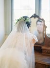 Femme en robe de mariée regardant miroir — Photo de stock