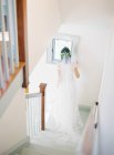 Женщина в свадебном платье стоит на лестнице — стоковое фото