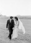 Couple nouvellement marié marchant dans le champ — Photo de stock