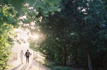 Recém-casados caminhando na estrada rural — Fotografia de Stock