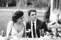 Пара за свадебным столом смотрит в сторону — стоковое фото