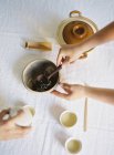 Hands taking tea leaves from bowl — Stock Photo