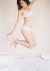 Mulher em lingerie requintada pulando na cama — Fotografia de Stock