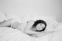Mujer en ropa interior exquisita acostada en la cama - foto de stock