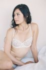 Mulher em lingerie requintada sentado na cama — Fotografia de Stock
